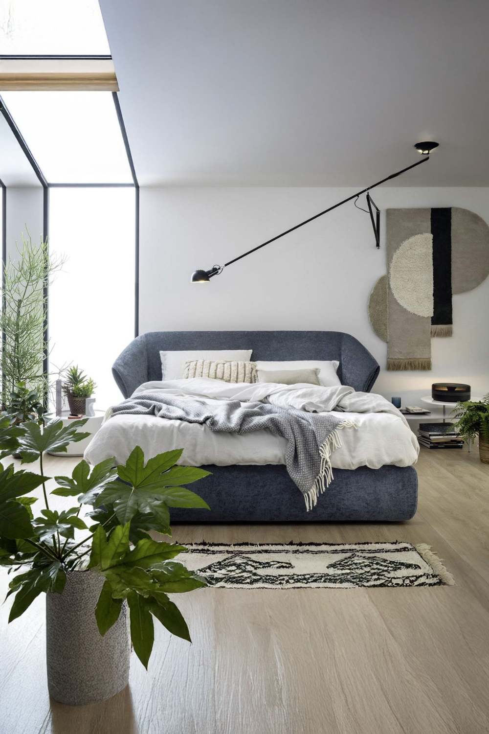 komfortabel-eingerichtetes-schlafzimmer-mit-einem-grossen-polsterbett-und-mehreren-pflanzen