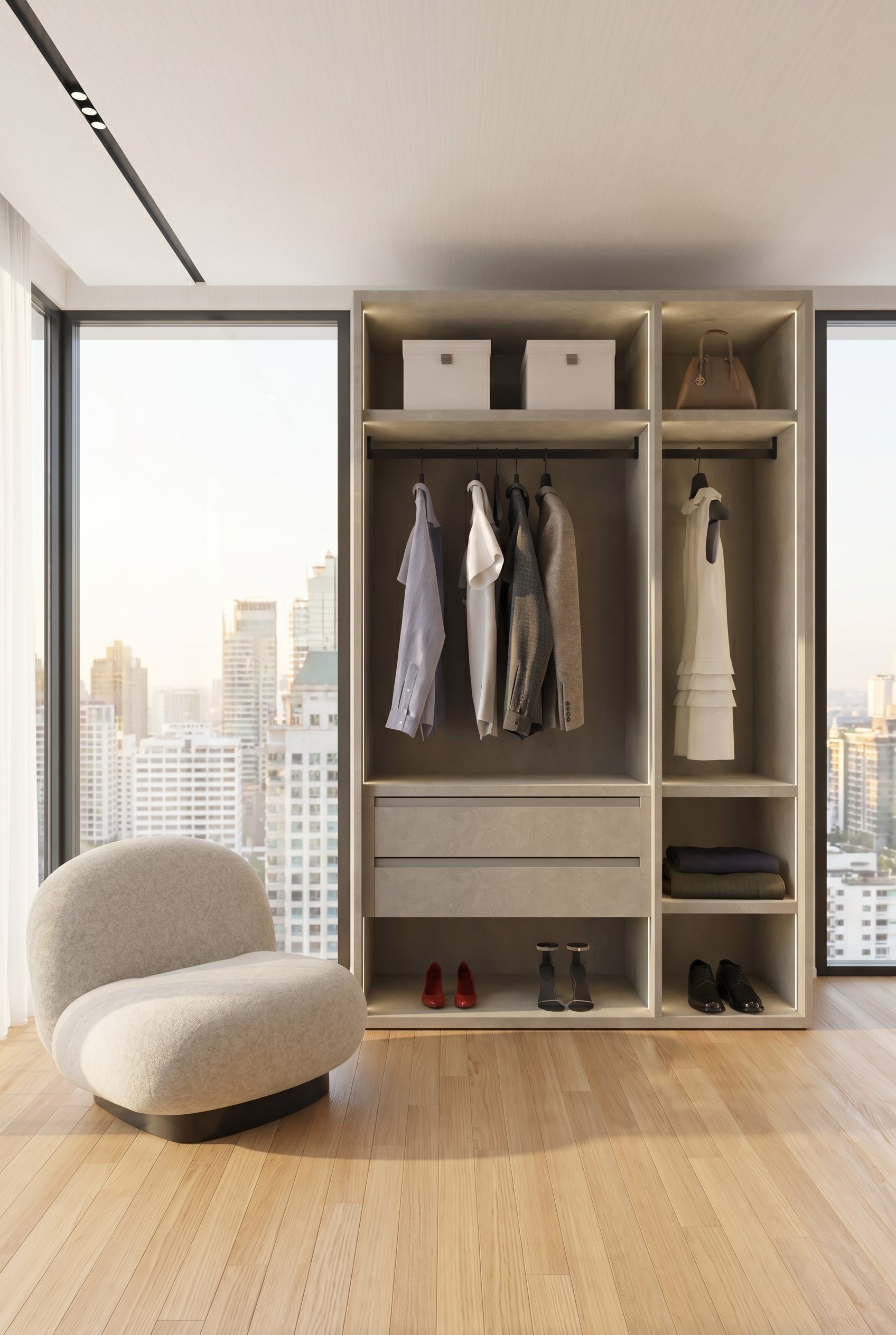 Modernes Ankleidezimmer mit einem rahmenlosen offenen Kleiderschranksystem in strukturiertem Greige, hängenden Leinenhemden und einem Lounge-Sessel im warmen Morgenlicht