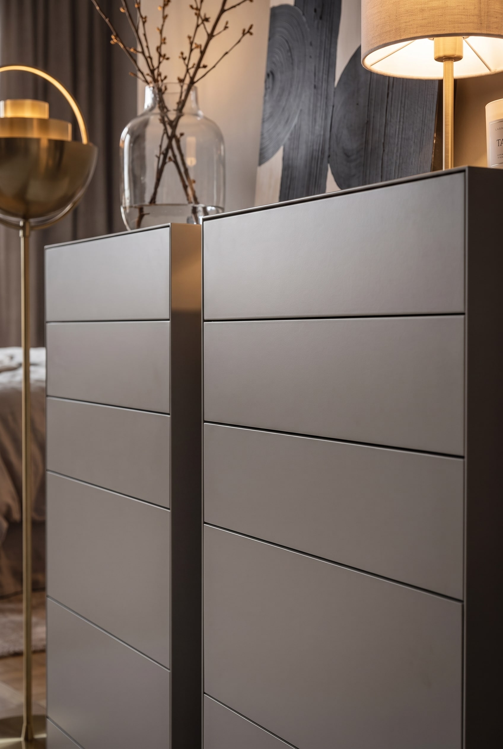 Two handleless, matte lacquered tall chests of drawers stand close together, forming an exact shadow gap.