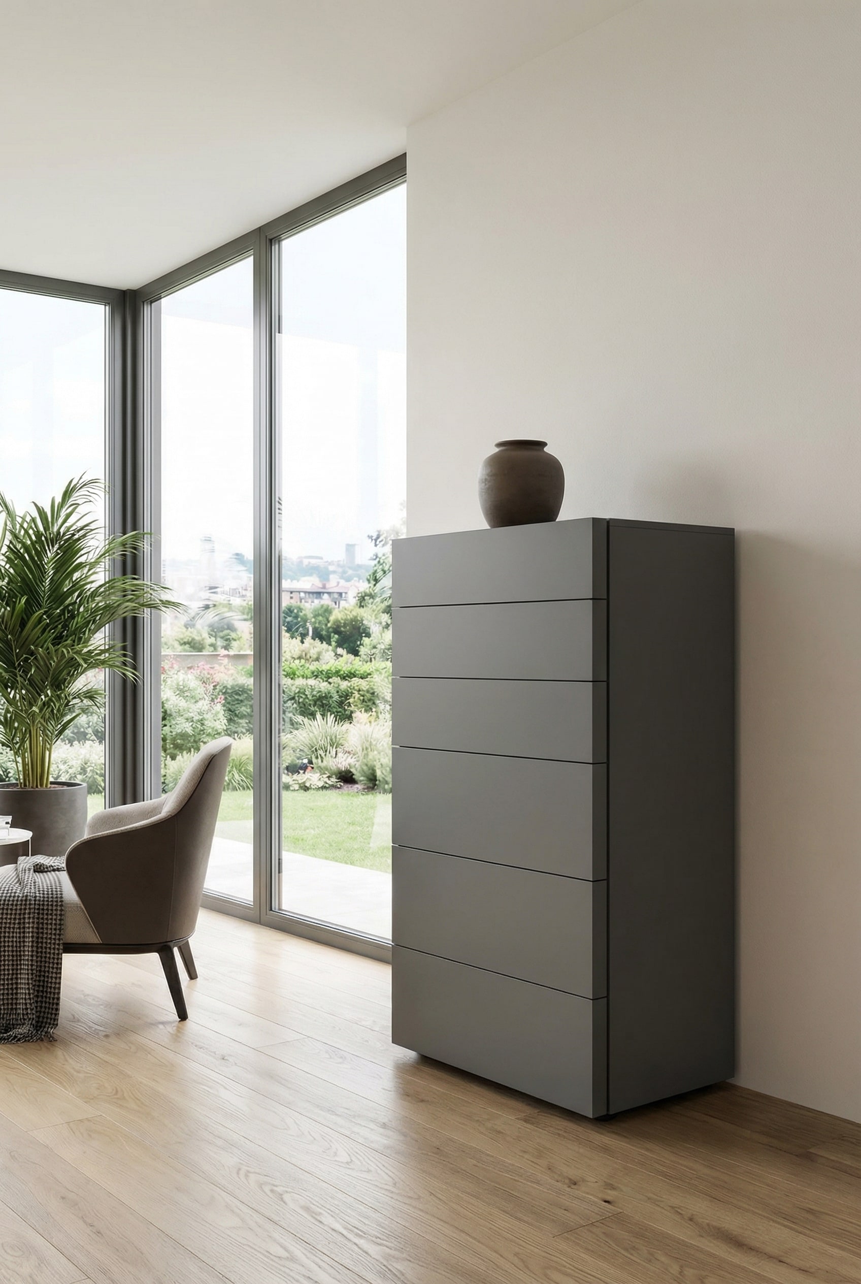 Eine moderne, grifffreie Hochkommode in edlem Dunkelgrau matt, die vor einer hellen Wand als minimalistisches und kontrastreiches M&ouml;belst&uuml;ck inszeniert wird.