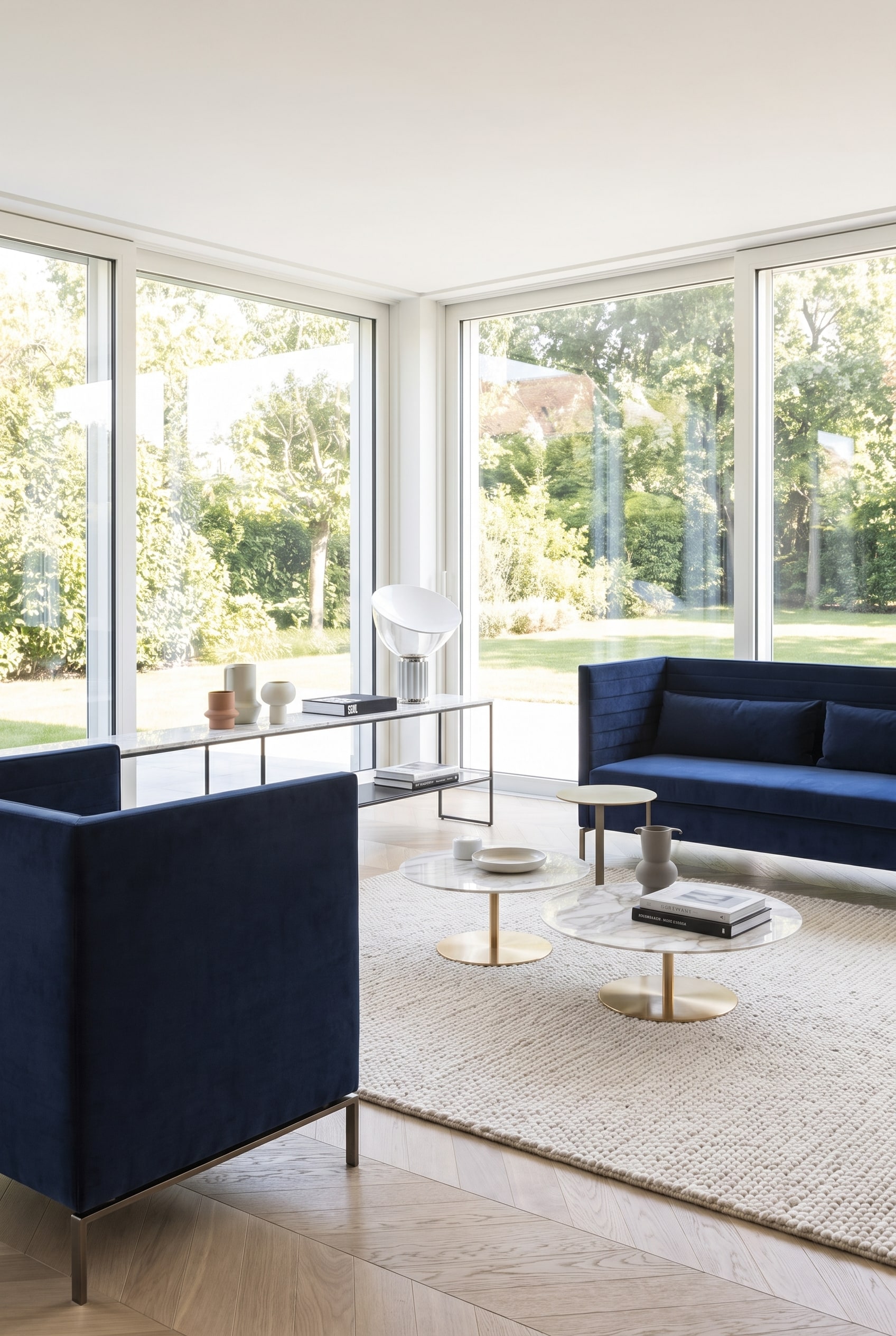 Großzügig wirkendes Wohnzimmer mit einem dunkelblauen, filigranen Sofa auf schlanken Metallkufen, das den hellen Holzboden sichtbar lässt.