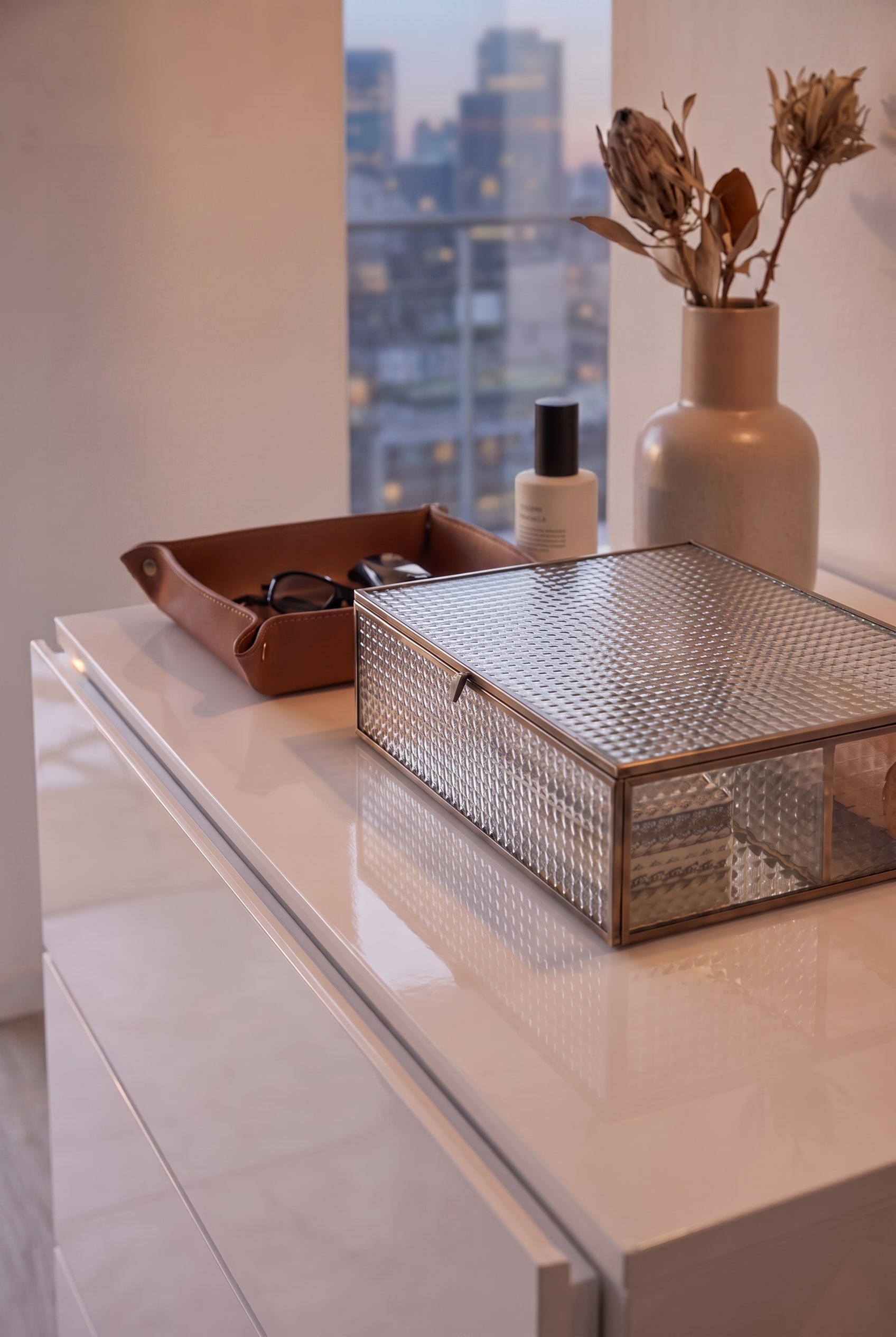 Top view of a white high-gloss chest of drawers with a glass box and leather tray, presented purely without a clothes rail.