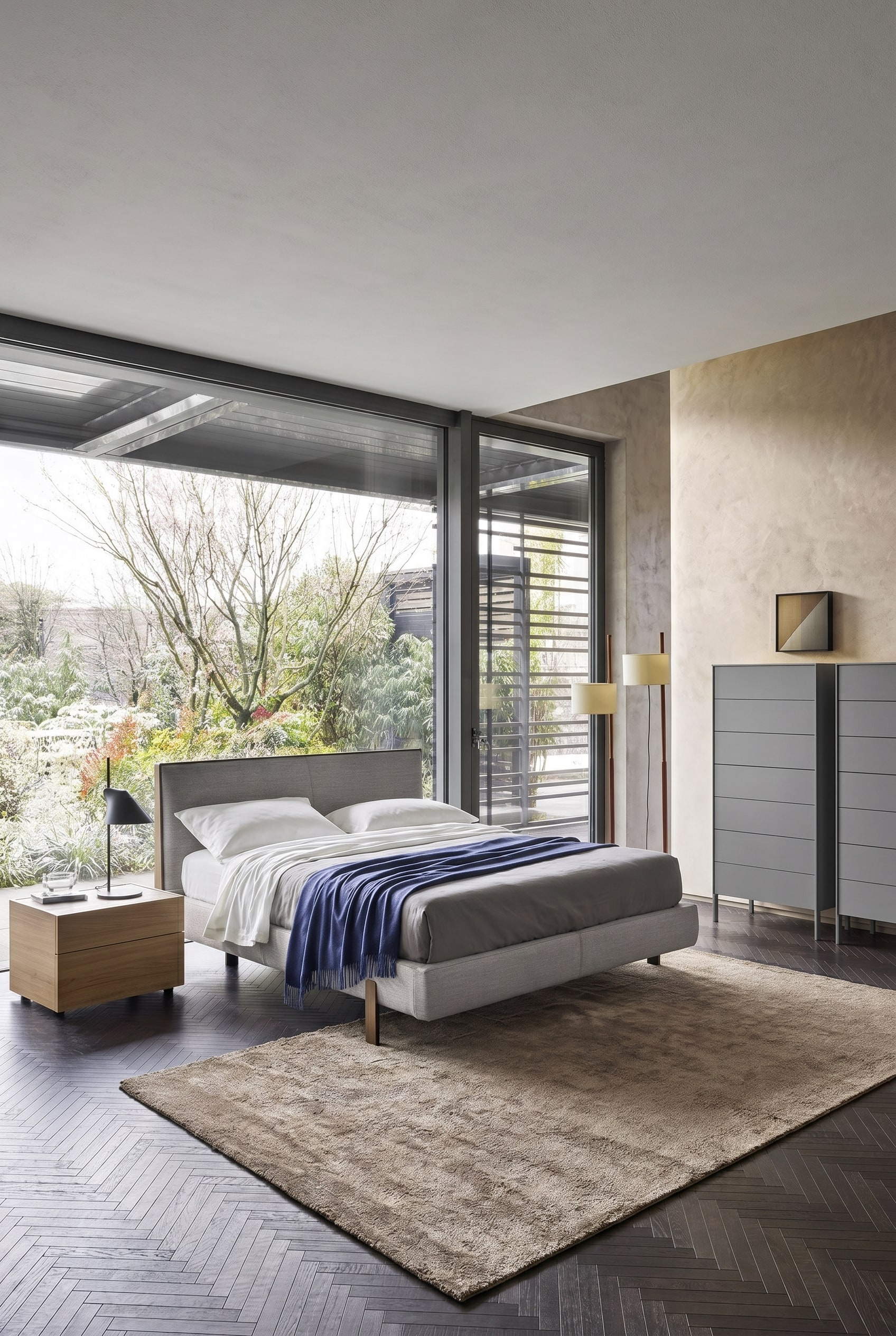 Elegantes Schlafzimmer mit bodentiefen Fenstern und einer modernen grauen Hochkommode auf schlanken Metallfüßen