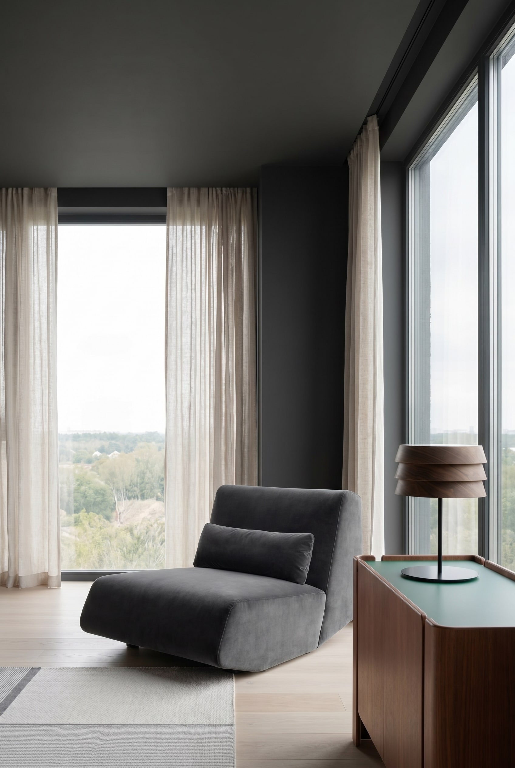 Modernes Wohnzimmer mit samtigem tiefen Lounge Sessel in Dunkelgrau und nahtlos dunkel gestrichenen W&auml;nden
