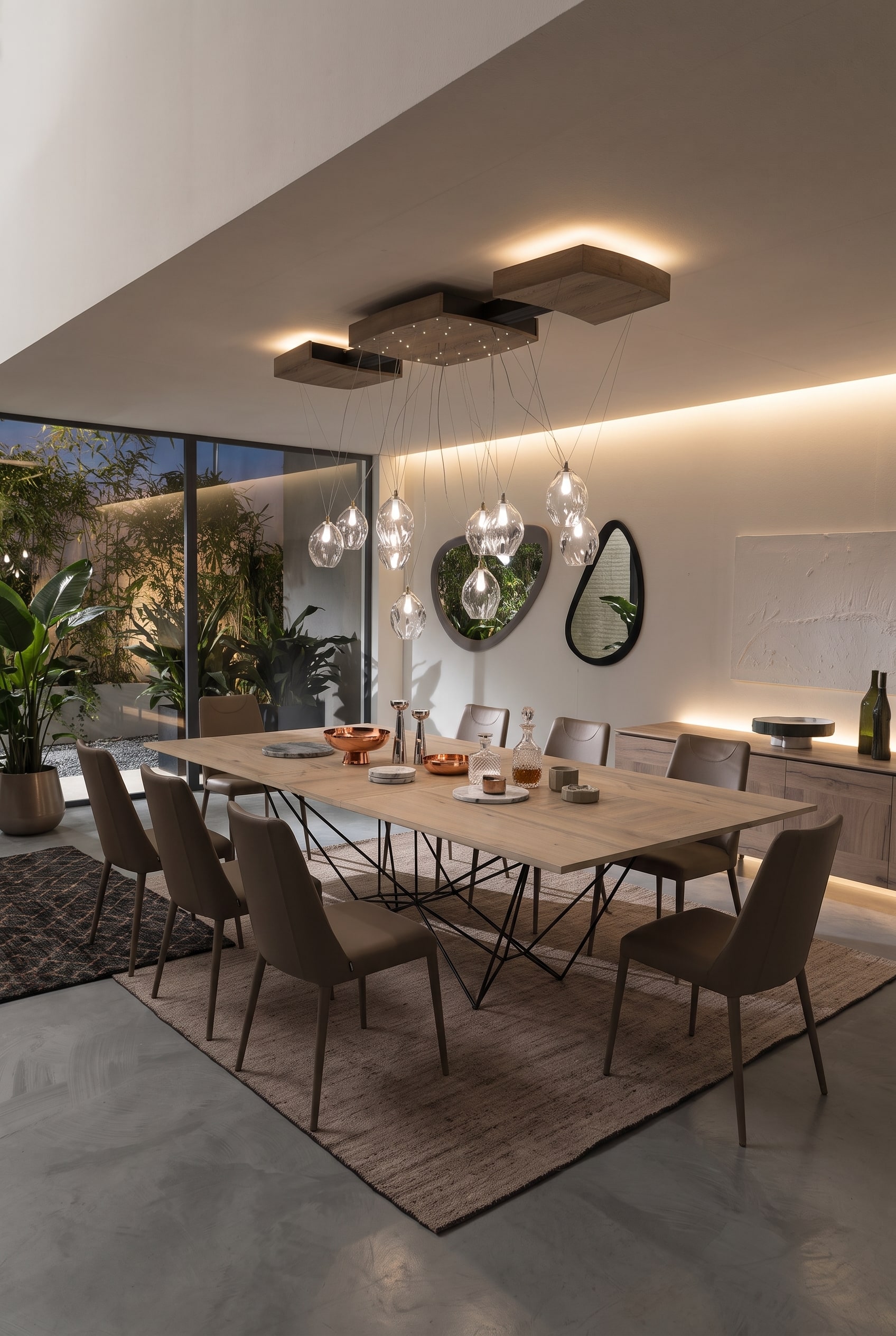 Modernes offenes Esszimmer mit gro&szlig;em Esstisch auf geometrischem Metallgestell, vier taupefarbenen St&uuml;hlen und Holz-Sideboard