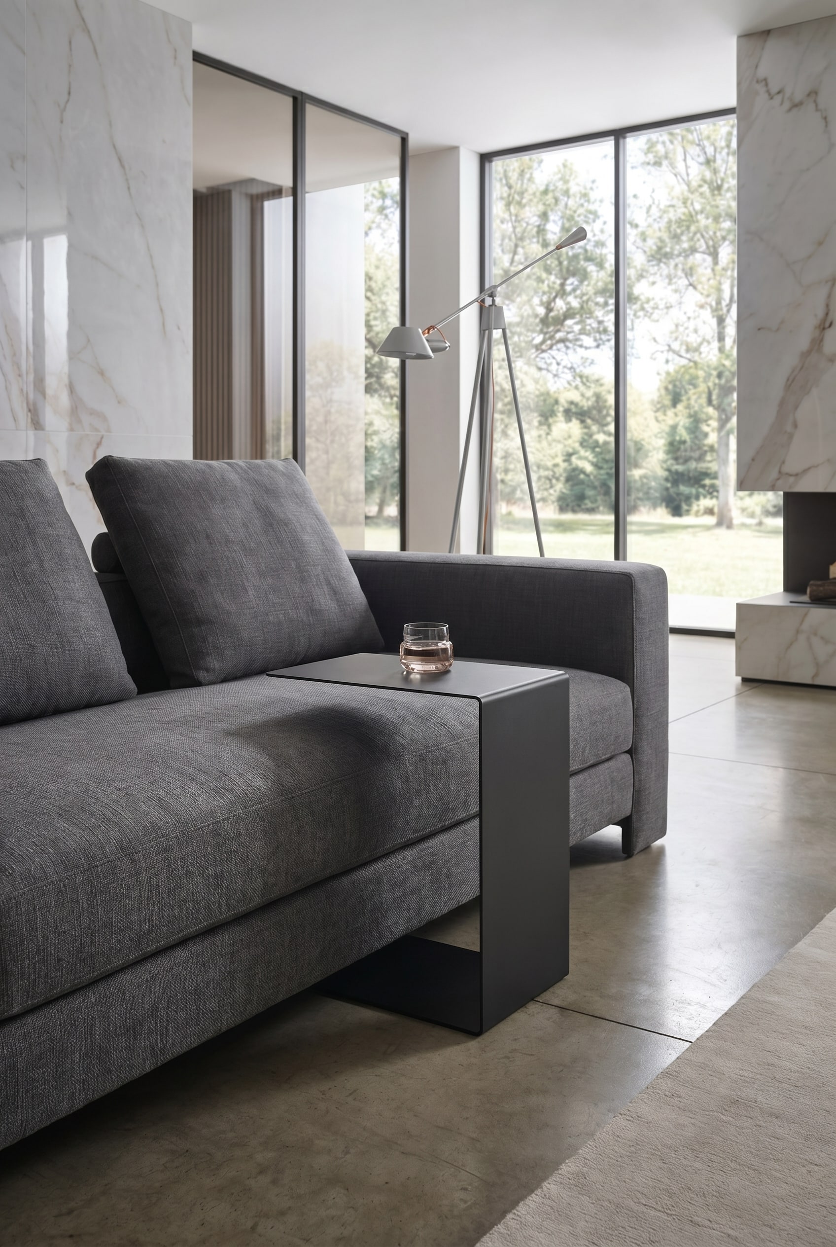 Detailaufnahme eines grauen Stoffsofas mit einem schwarzen, minimalistischen C-förmigen Beistelltisch aus Metall