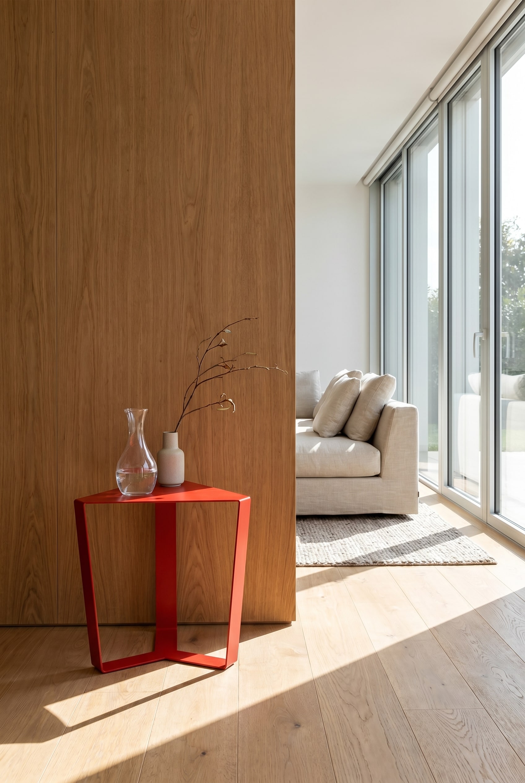 Minimalist geometric side table made of thin red metal in front of a massive wall with wood panels