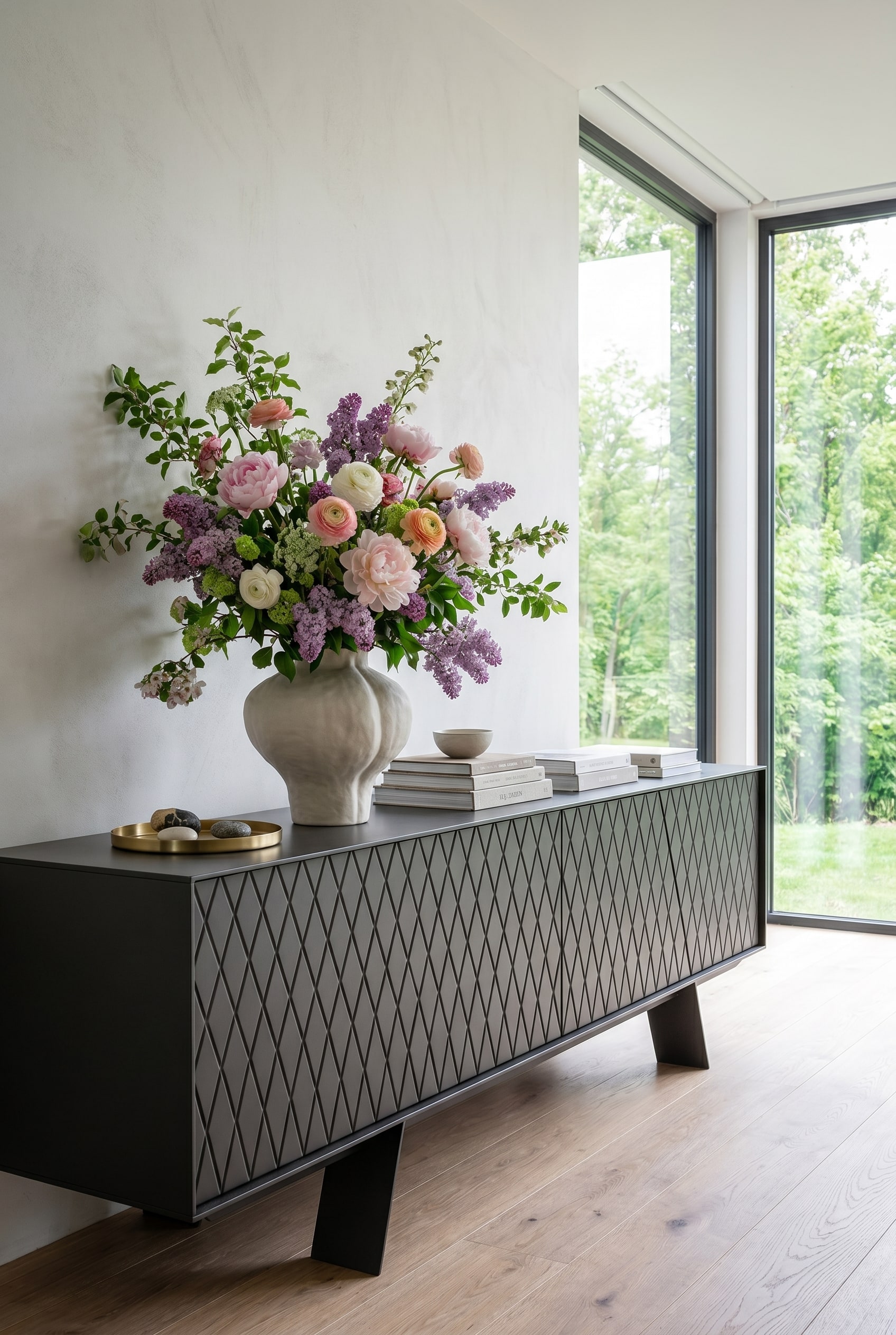 Minimalistisches Wohnzimmer mit bodentiefen Fenstern, hellem Tageslicht und einem eleganten niedrigen Sideboard, auf dem eine voluminöse Frühlingsvase steht Minimalistisches Wohnzimmer mit bodentiefen Fenstern, hellem Tageslicht und einem eleganten niedrigen Sideboard, auf dem eine voluminöse Frühlingsvase steht
