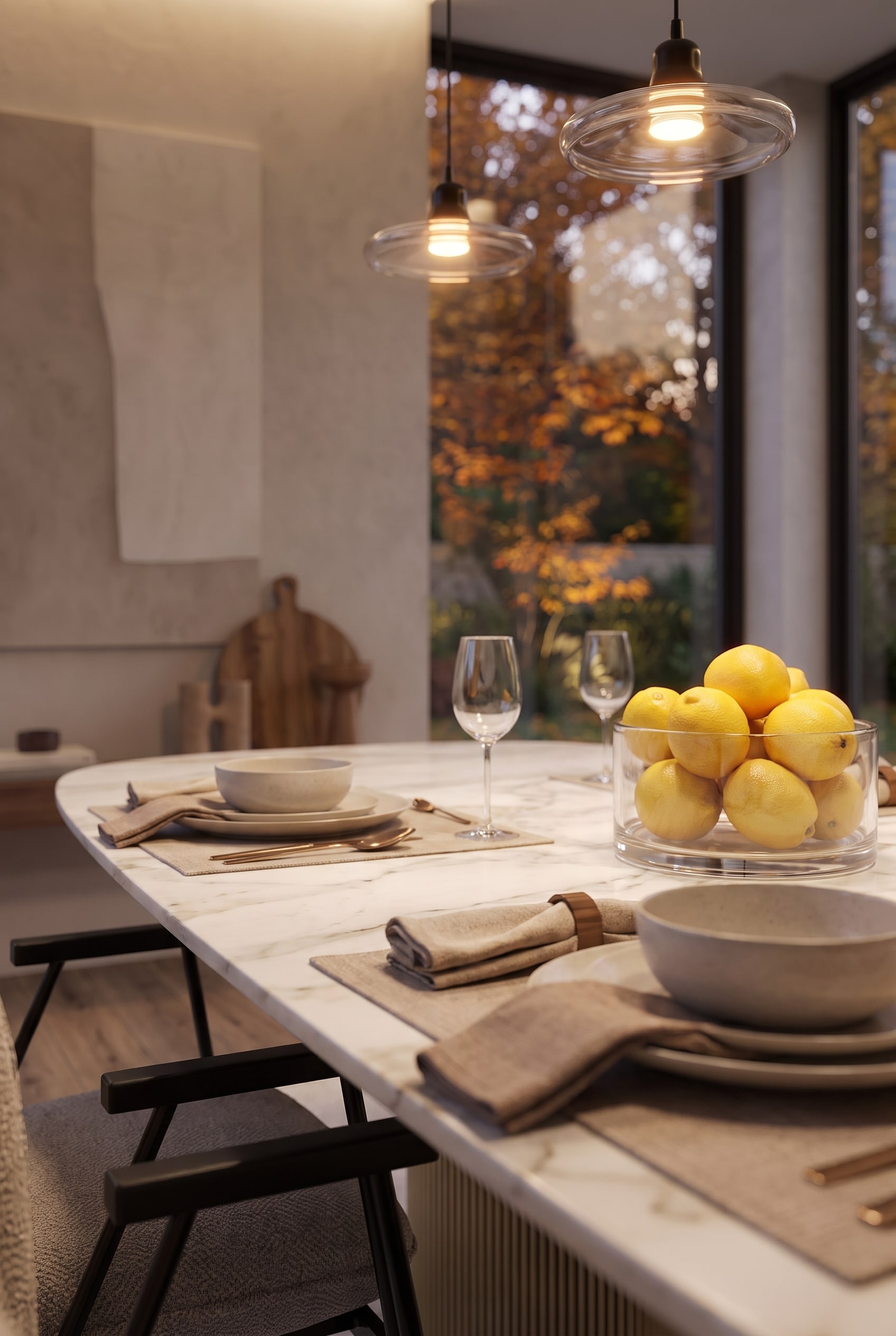 Side perspective over the dining table with focus on a glass bowl full of lemons and low-hanging glass pendant lights.