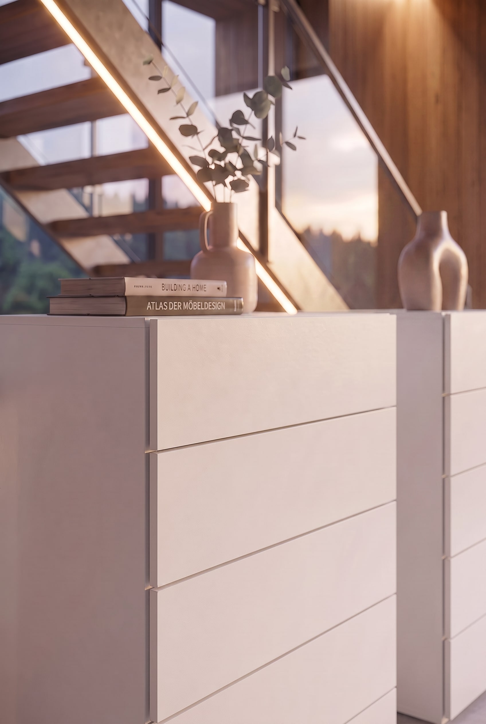 Detail of a white chest of drawers with design books and a ceramic vase in warm sunlight.