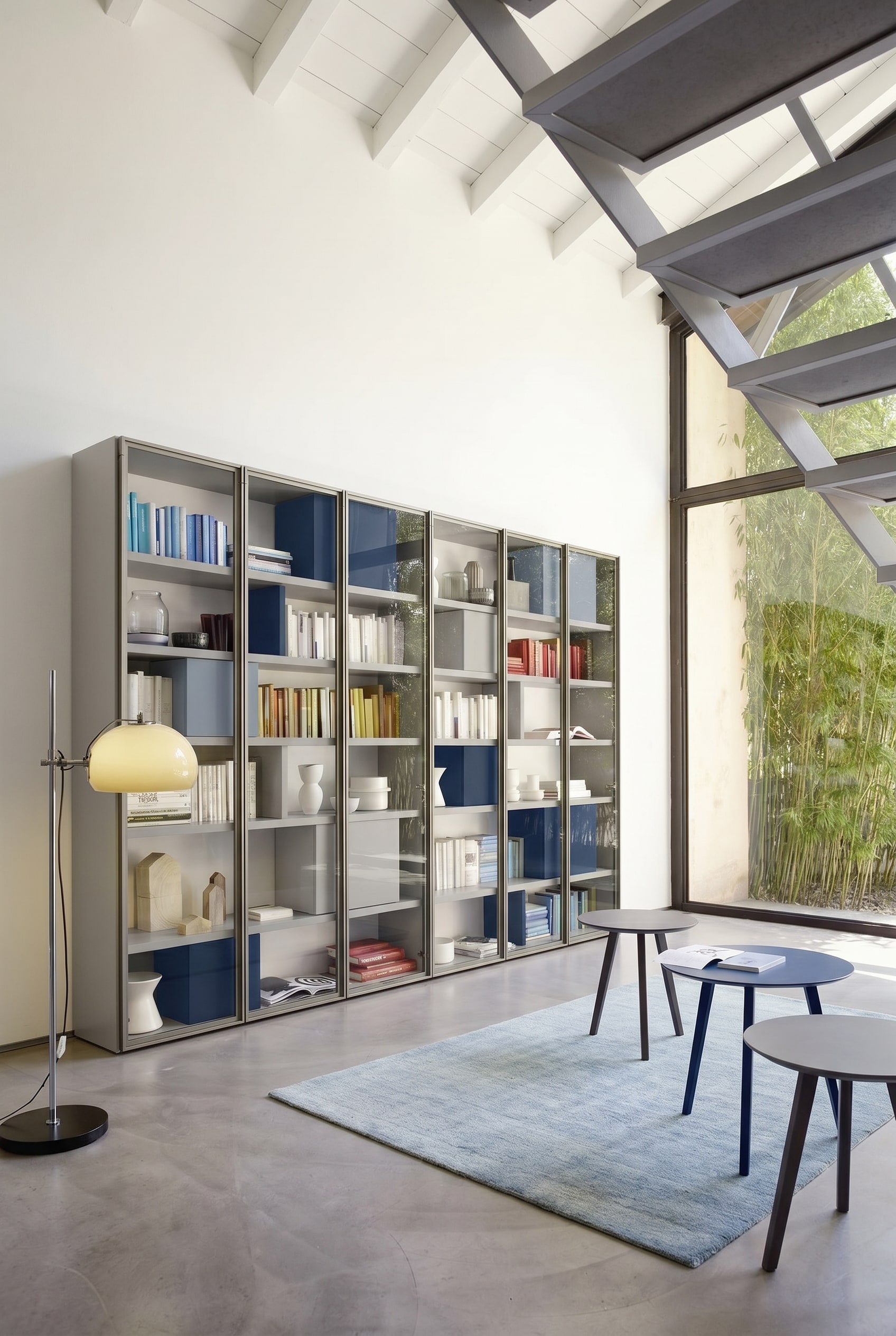 Light gray custom-made bookshelf with minimal shelf spacing and integrated blue boxes