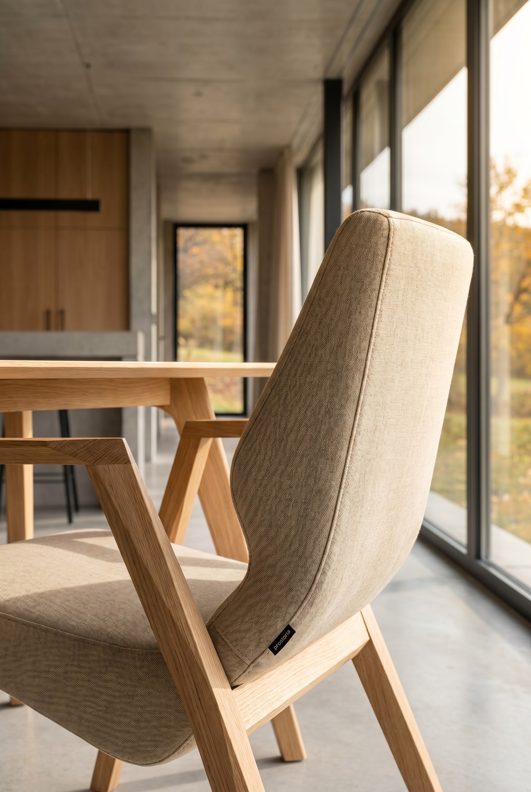 Elegantes Esszimmer mit einem Prostoria Oblique Sessel mit Holzgestell am Kopfende vor bodentiefen Fenstern