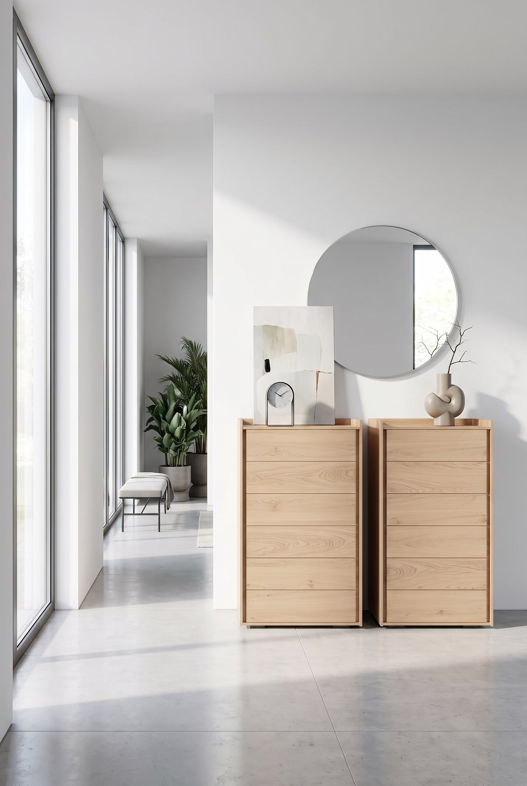 Narrow tall chest of drawers made of light wood in the hallway, with a noble table clock and a minimalist painting leaning on the top plate