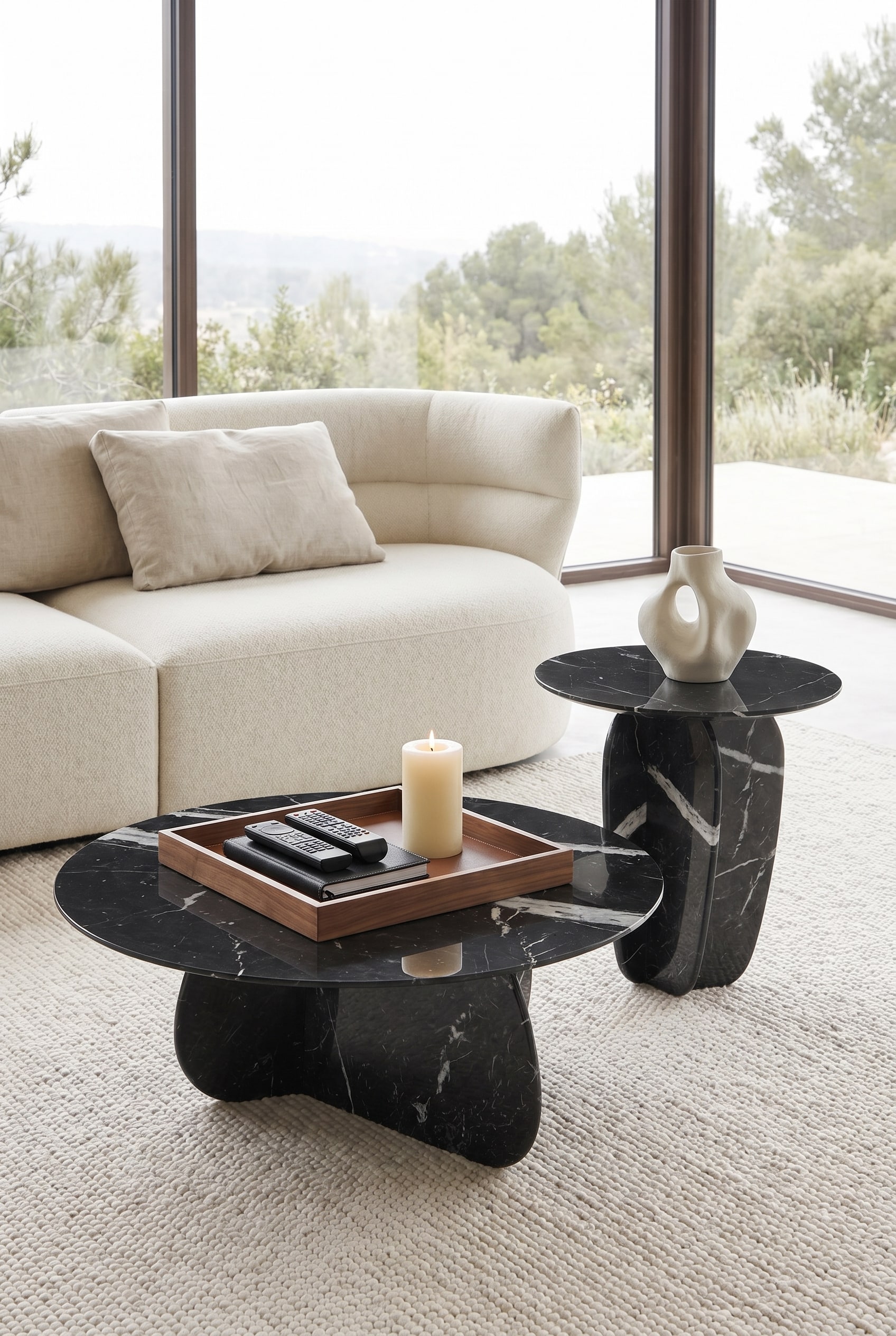 Modernes Wohnzimmer mit organisch geformtem Marmor-Couchtisch, darauf ein quadratisches Holztablett mit Fernbedienung und Stumpenkerze
