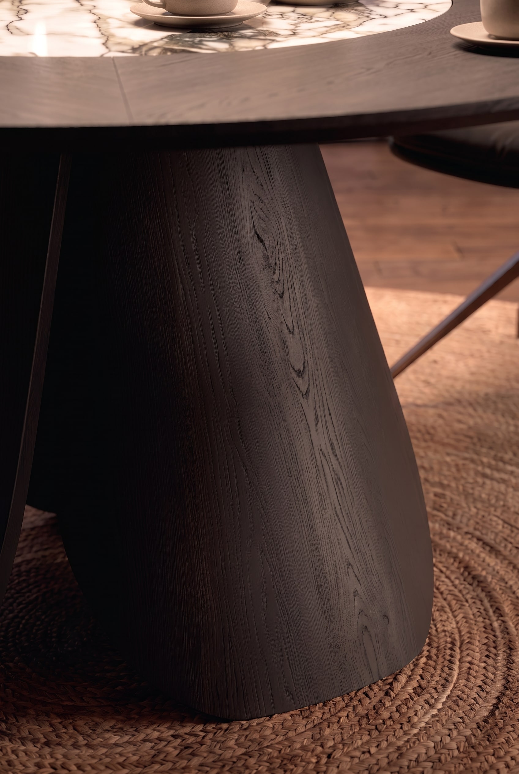 Detail shot of the massive, inwardly curved table leg made of dark stained wood with visible grain.